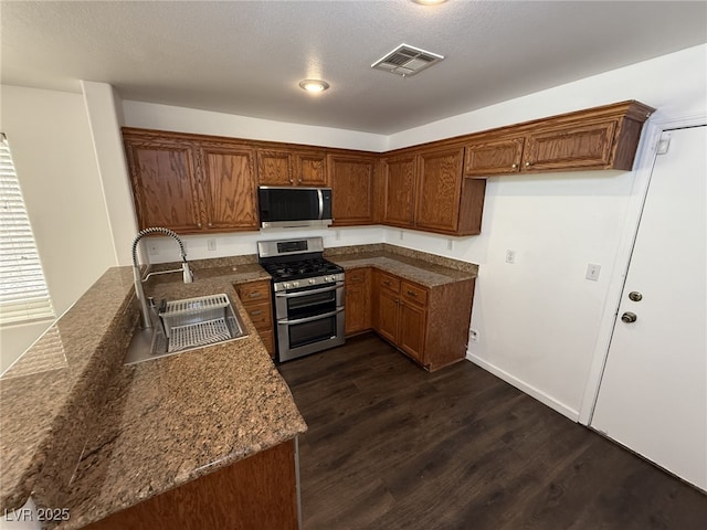 5661 Bonds Flat St, Las Vegas, NV 89148 - kitchen with range with two ovens, a sink, brown cabinetry, dark wood finished floors, and a peninsula