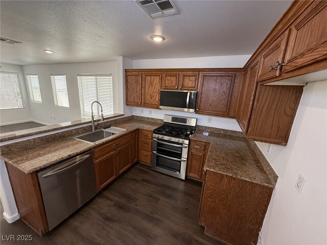 5661 Bonds Flat St, Las Vegas, NV 89148 - kitchen with appliances with stainless steel finishes, a sink, dark countertops, dark wood finished floors, and brown cabinetry