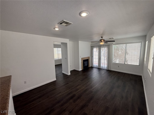 5661 Bonds Flat St, Las Vegas, NV 89148 - unfurnished living room featuring baseboards, dark wood-style floors, a ceiling fan, a tile fireplace, and a textured ceiling