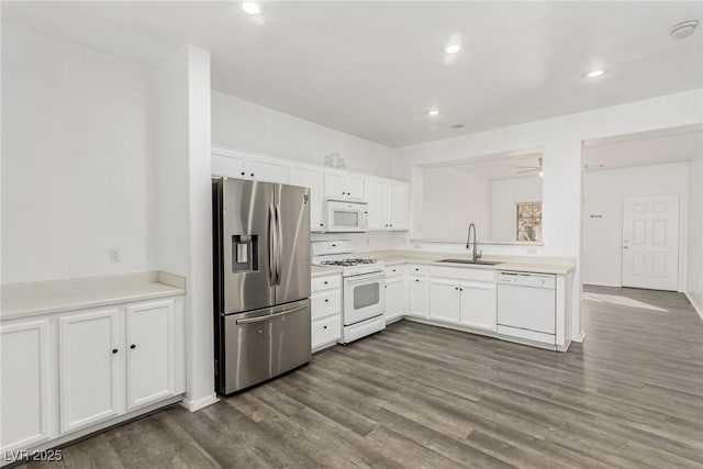 kitchen featuring dark wood-type flooring, light countertops, white cabinets, white appliances, and a sink