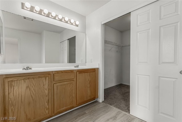 bathroom featuring double vanity, wood finished floors, visible vents, and a sink