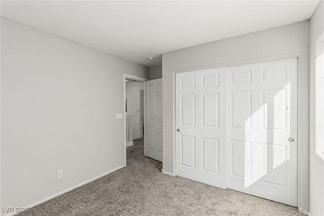 unfurnished bedroom with a closet, baseboards, and carpet flooring