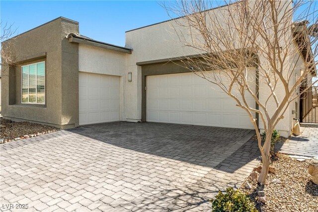 exterior space featuring decorative driveway, a garage, and stucco siding