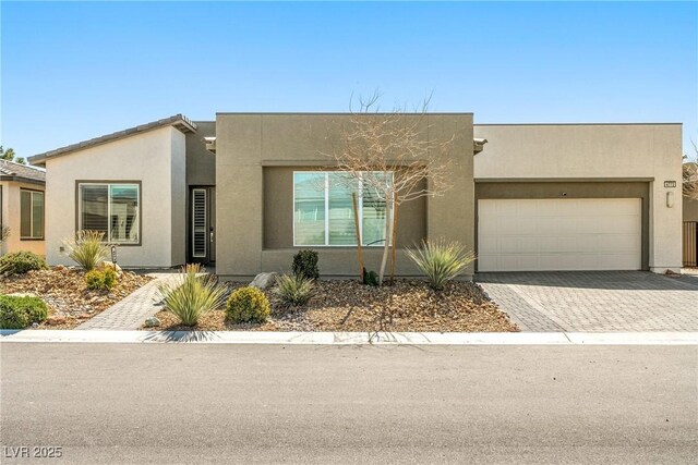 view of front facade with a garage, driveway, and stucco siding