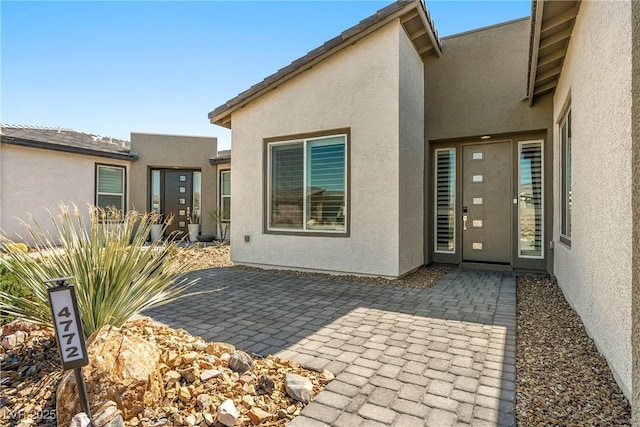 doorway to property featuring a patio area and stucco siding