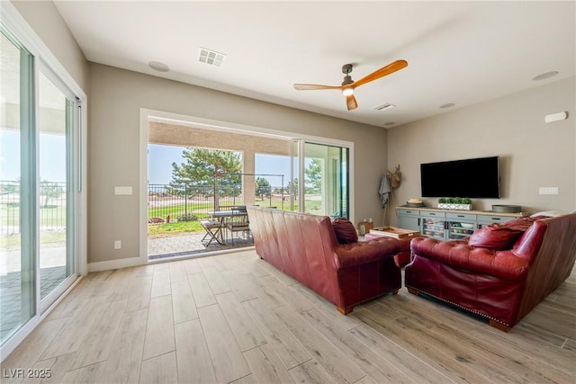living room with visible vents, ceiling fan, light wood-style floors, and baseboards