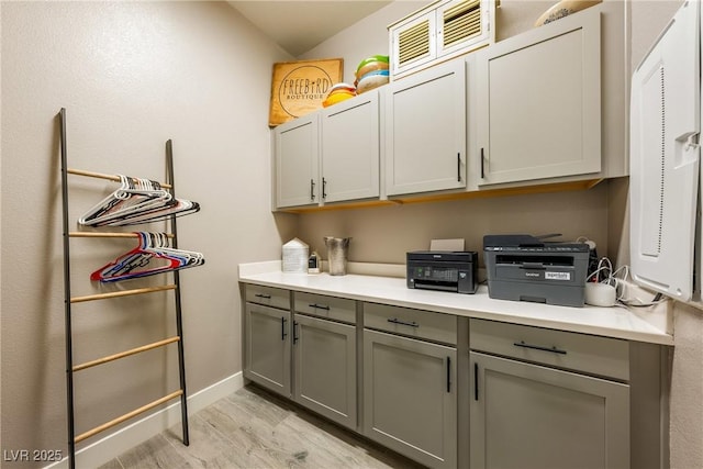 laundry area with light wood-style flooring and baseboards