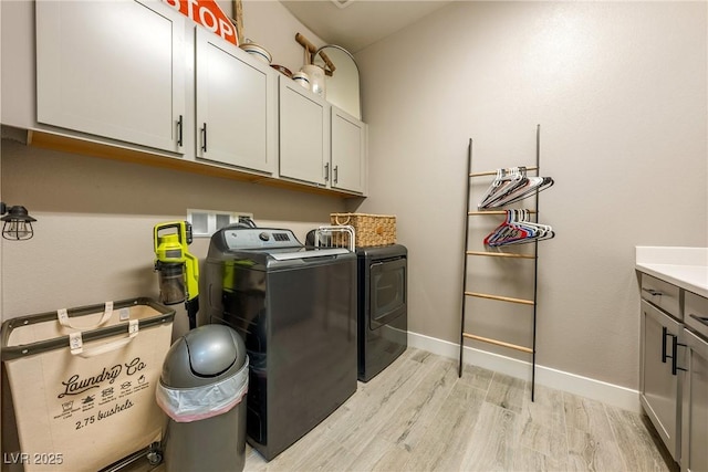 washroom featuring light wood-style floors, separate washer and dryer, baseboards, and cabinet space