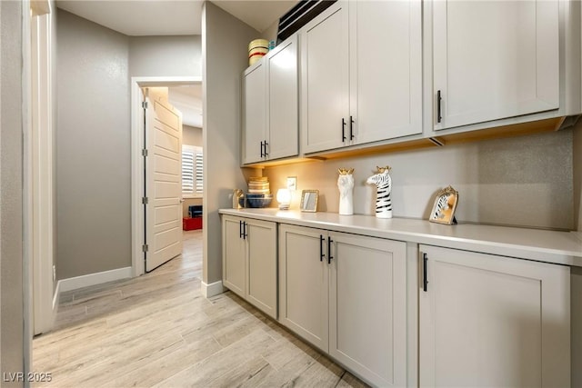 bar featuring light wood-style floors and baseboards