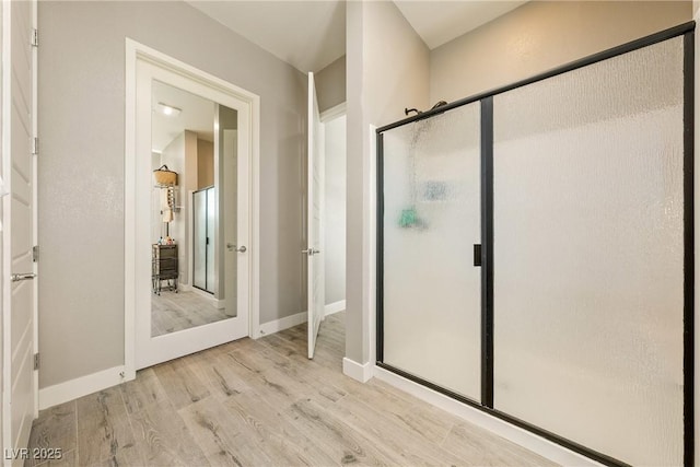 bathroom with a shower stall, baseboards, and wood finished floors