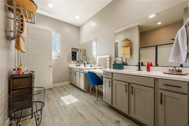 full bath featuring two vanities, recessed lighting, wood finished floors, a sink, and baseboards