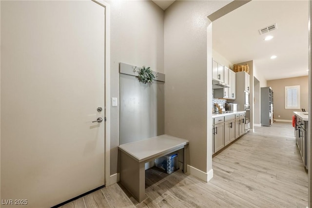 mudroom with light wood-style floors, baseboards, visible vents, and recessed lighting