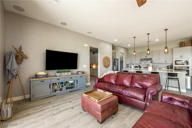living room featuring baseboards, recessed lighting, and light wood-style floors