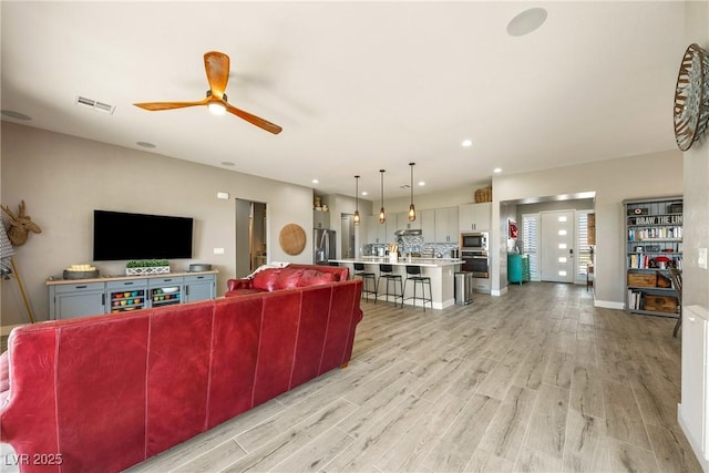 living area featuring baseboards, recessed lighting, light wood-style flooring, a ceiling fan, and visible vents