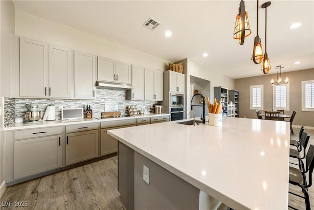 kitchen featuring visible vents, light countertops, appliances with stainless steel finishes, a breakfast bar, and decorative backsplash
