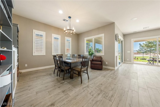 dining area featuring visible vents, baseboards, light wood-type flooring, and a notable chandelier