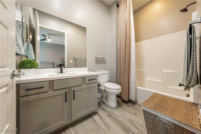 full bathroom featuring toilet, ceiling fan, shower / bathtub combination with curtain, vanity, and wood finished floors