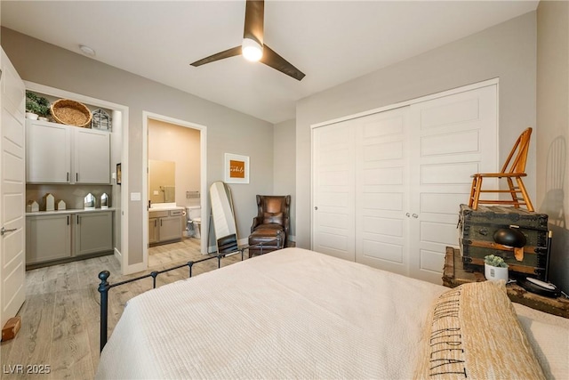 bedroom with baseboards, a closet, ensuite bath, a ceiling fan, and light wood-style floors