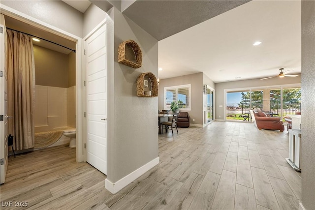 corridor featuring light wood finished floors and baseboards