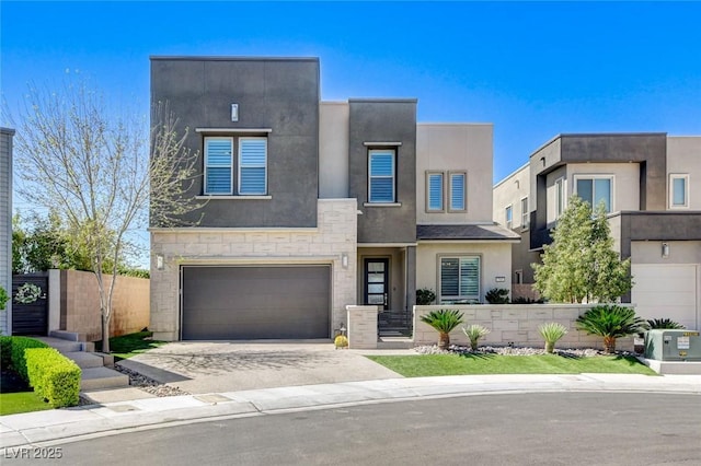 contemporary home featuring stone siding, driveway, fence, a garage, and stucco siding