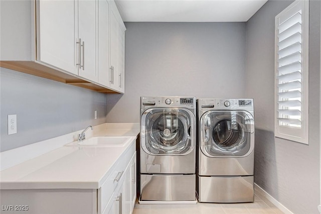 clothes washing area with washing machine and clothes dryer, cabinet space, a sink, and baseboards