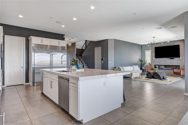 kitchen featuring appliances with stainless steel finishes, light tile patterned flooring, white cabinets, and a sink