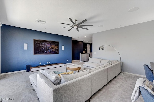 living area with visible vents, baseboards, light colored carpet, and ceiling fan