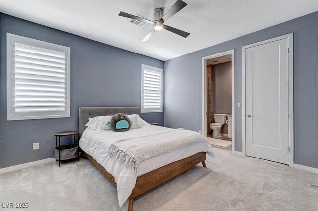 carpeted bedroom featuring baseboards, ensuite bathroom, visible vents, and ceiling fan