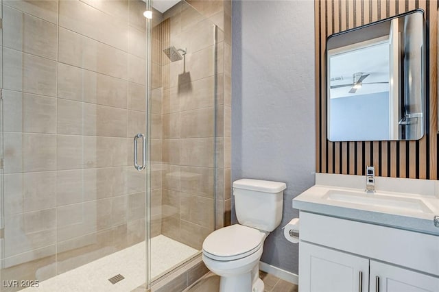 bathroom featuring a shower stall, baseboards, toilet, and vanity