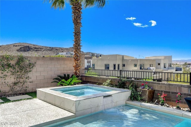 view of swimming pool with a fenced backyard, an in ground hot tub, and a mountain view