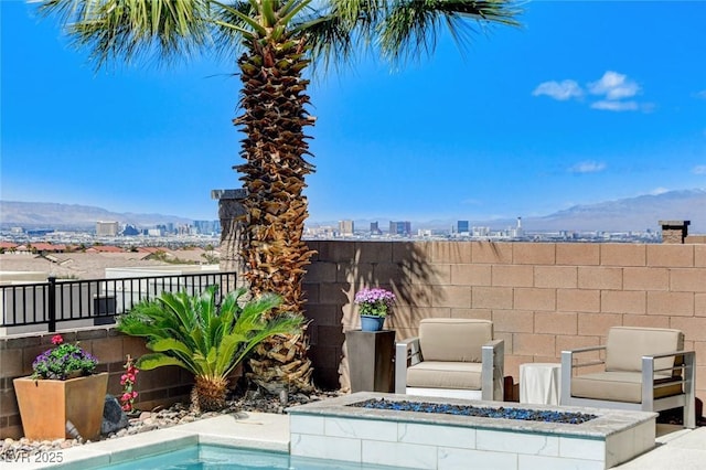view of swimming pool with a fire pit, a view of city, and fence