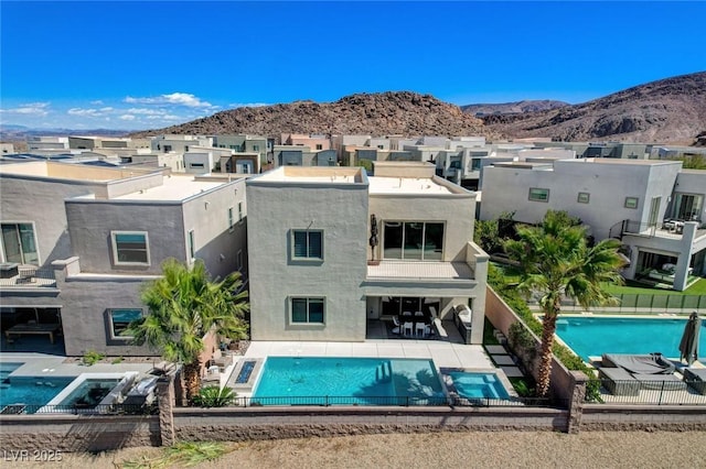 rear view of property with a fenced in pool, fence, a balcony, a patio, and a mountain view