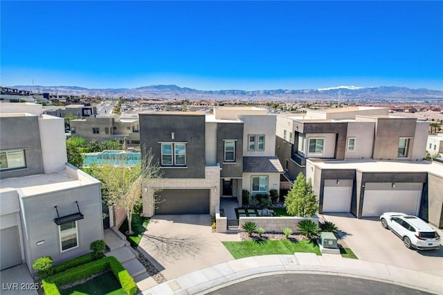 view of front of home featuring a residential view, stucco siding, concrete driveway, and a mountain view