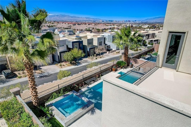 exterior space with a mountain view, fence, a pool with connected hot tub, and a residential view