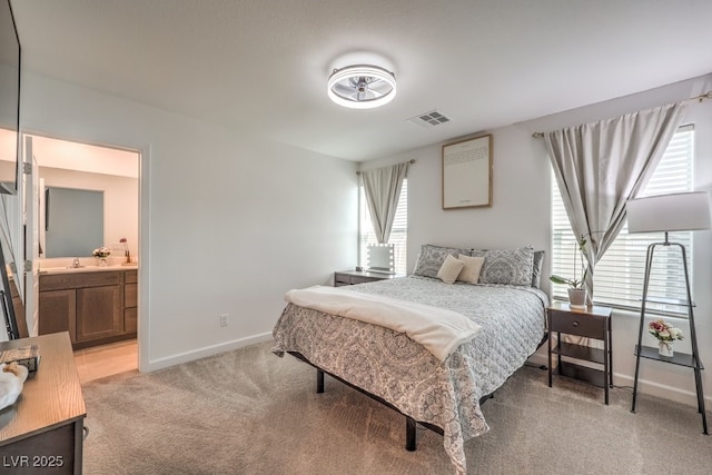 bedroom with light carpet, visible vents, connected bathroom, and baseboards