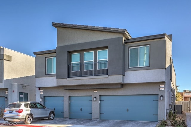 view of front of property featuring stucco siding, driveway, central AC, and an attached garage