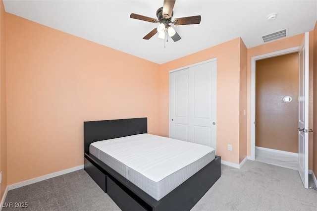 bedroom featuring visible vents, a closet, baseboards, light colored carpet, and a ceiling fan
