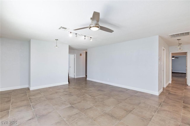 spare room with track lighting, baseboards, a ceiling fan, and visible vents