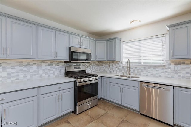 kitchen with a sink, gray cabinets, stainless steel appliances, and tasteful backsplash