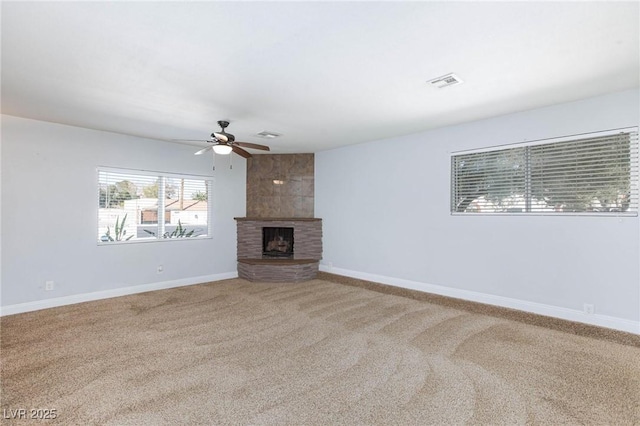 unfurnished living room with visible vents, a fireplace, baseboards, ceiling fan, and carpet