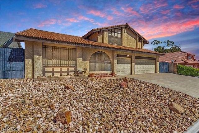 view of front facade featuring driveway, fence, a tile roof, and stucco siding