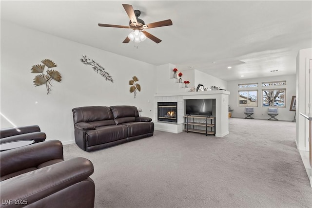 carpeted living room featuring a tiled fireplace and ceiling fan