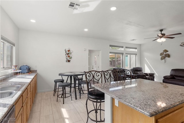 kitchen with open floor plan, a kitchen bar, a sink, visible vents, and dishwasher