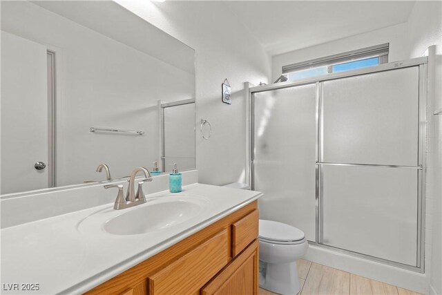 bathroom with a shower stall, toilet, and vanity
