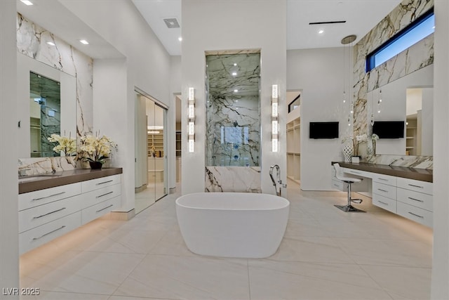 bathroom with a freestanding tub, a marble finish shower, a high ceiling, and vanity