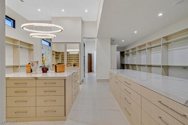 spacious closet featuring light tile patterned flooring and a notable chandelier