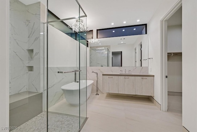bathroom featuring a marble finish shower, vanity, a chandelier, a freestanding bath, and recessed lighting
