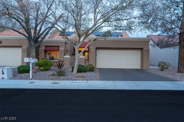 view of front of house with aphalt driveway, a garage, and stucco siding