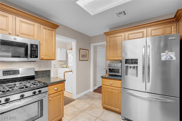 kitchen featuring washing machine and clothes dryer, visible vents, appliances with stainless steel finishes, and dark countertops