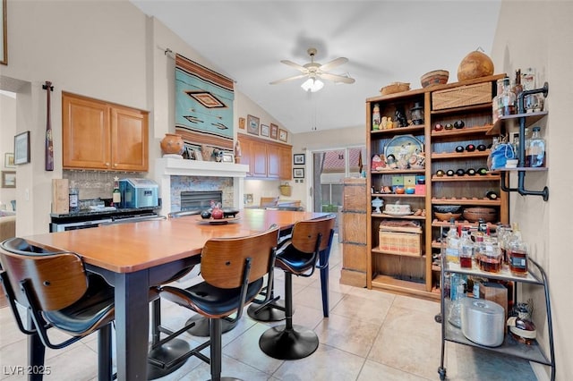 kitchen featuring a center island, ceiling fan, a breakfast bar, lofted ceiling, and light tile patterned flooring